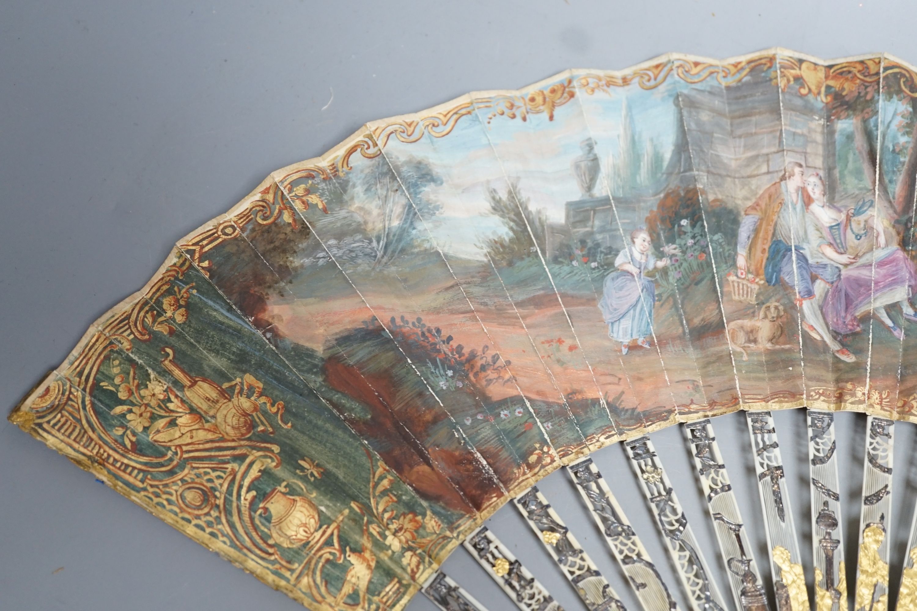 Two late 18th/early 19th century French gilded and silvered ivory and painted paper leaf fans